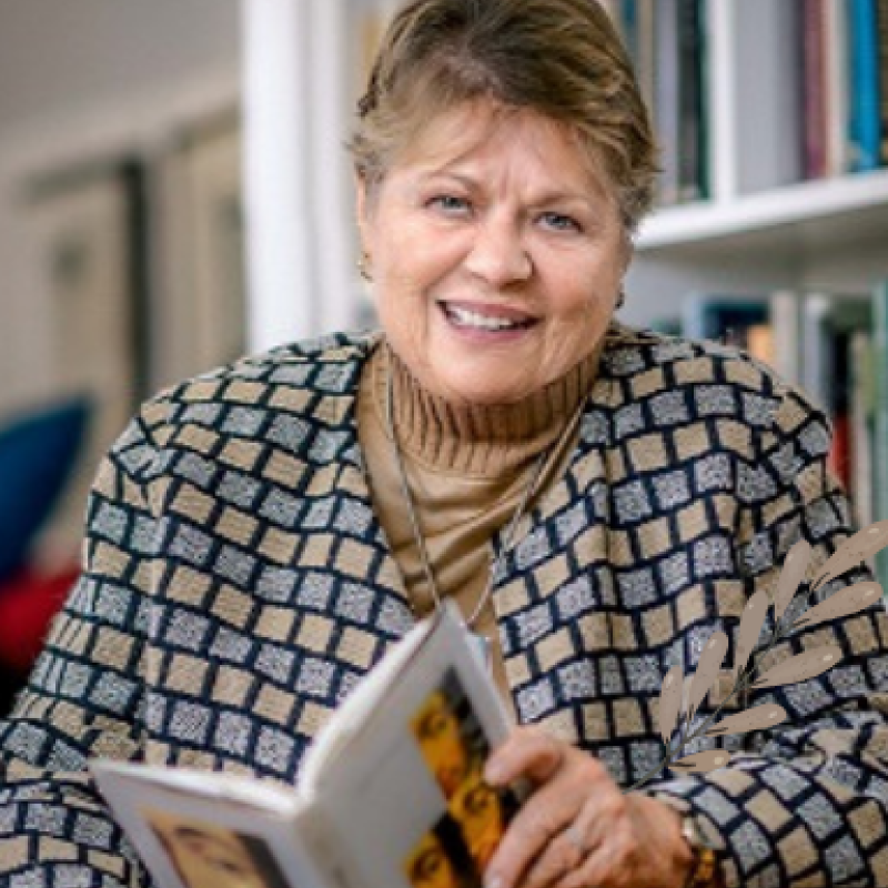 An image of Margaret Jacob, smiling and looking at the camera while holding a book.