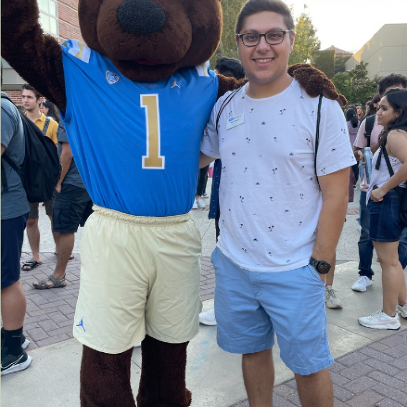 Image of Nadir Fouani smiling and posing with Joe Bruin (UCLA Brown Bear mascot)]